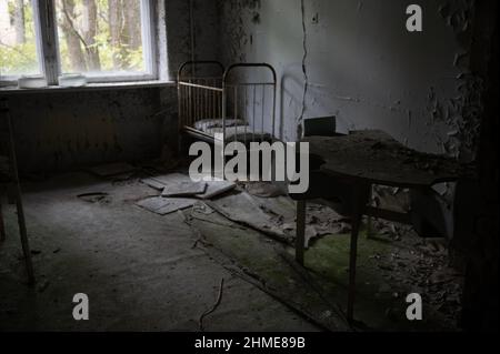 Letti abbandonati in un vivaio in un ospedale in decadenza a Pripyat, Ucraina, vicino alla centrale nucleare di Chernobyl. Foto Stock