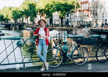 Donna positiva in piedi vicino alle biciclette sul ponte Foto Stock