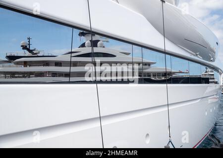 Riflesso di una barca su una superficie lucida di un grande yacht in giorno di sole, il corrimano cromato, megayacht è ormeggiato nel porto Foto Stock