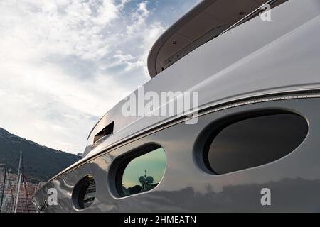 Riflesso di una barca su una superficie lucida di un enorme yacht al tramonto, il corrimano cromato, megayacht è ormeggiato nel porto Foto Stock