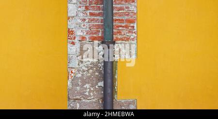 Vecchio downpipe in rame arrugginito e ghisa contro un muro in mattoni e gesso - immagine con spazio copia. Foto Stock