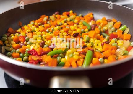 Cottura di verdure di mais, piselli, peperoni, fagioli da vicino. Messa a fuoco selettiva Foto Stock