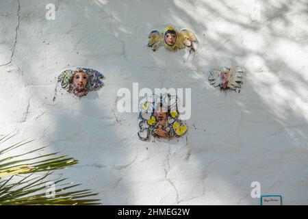 Facce di ceramica persone attaccate a una parete di stucco da Marge Dunlap di Santa Barbara artista. Le sue piccole immagini di ceramica persone sono luoghi in out-of-the-wa Foto Stock