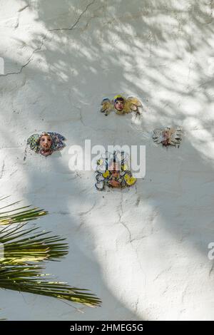 Facce di ceramica persone attaccate a una parete di stucco da Marge Dunlap di Santa Barbara artista. Le sue piccole immagini di ceramica persone sono luoghi in out-of-the-wa Foto Stock