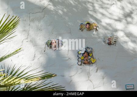 Facce di ceramica persone attaccate a una parete di stucco da Marge Dunlap di Santa Barbara artista. Le sue piccole immagini di ceramica persone sono luoghi in out-of-the-wa Foto Stock