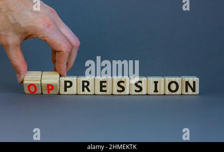 Pressione al simbolo di oppressione. L'uomo d'affari trasforma i cubi di legno, cambia la parola pressione in oppressione. Bellissimo sfondo grigio. Affari, pressione Foto Stock