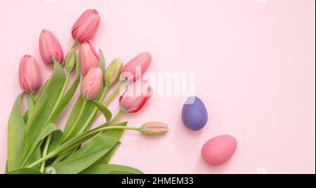 Buon biglietto di auguri di Pasqua. Bouquet di fiori di tulipano e uova color pastello su sfondo rosa, vista dall'alto, spazio copia. Festa di primavera. Foto Stock