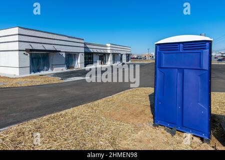 Scatto orizzontale di un gabinetto portatile sul bordo di un cantiere commerciale. Foto Stock