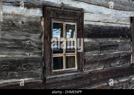 Casa rustica in legno di tronchi rotondi. Antico design delle finestre. Serramento in legno. Villaggio coperto di neve. Edifici secolari. Fotografia professionale. Foto Stock