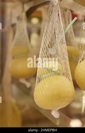 Delizioso Caciocavallo fresco e Scamorza formaggio appeso. Formaggi italiani da vicino. I formaggi sono fatti a mano. La produzione di formaggio Foto Stock