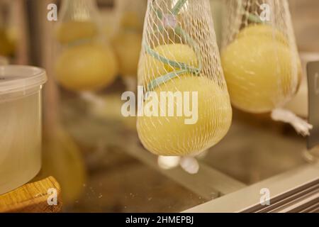 Delizioso Caciocavallo fresco e Scamorza formaggio appeso. Formaggi italiani da vicino. I formaggi sono fatti a mano. La produzione di formaggio Foto Stock