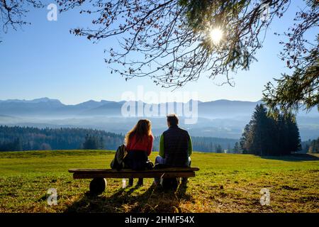 Escursionisti che si rompe su una panchina, sul Panoramaweg, a Sonnenbichel, Schoenberg, nei pressi di Rottenbuch, Pfaffenwinkel, Baviera superiore, Baviera, Germania Foto Stock