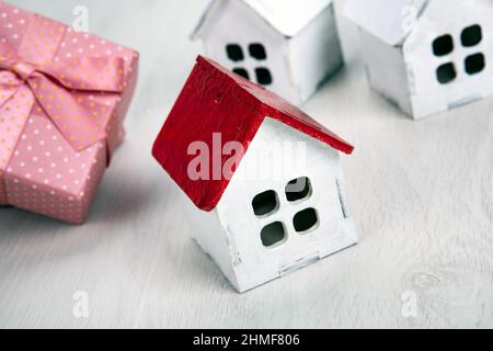 piccola casa di legno bianco con tetto rosso e scatola regalo primo piano Foto Stock