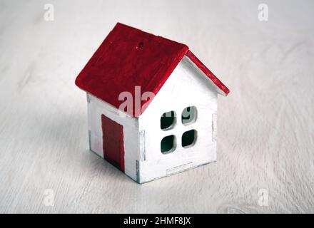 piccola casa di legno bianco con tetto rosso su sfondo di legno primo piano Foto Stock