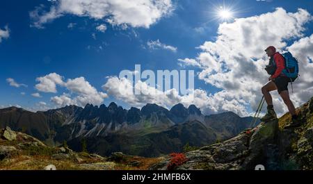 Alpinista in primo piano di fronte ad un panorama retroilluminato delle cime di Kalkkoegel, con le nubi drammatiche, Sellrain, Innsbruck, Tirolo, Austria Foto Stock