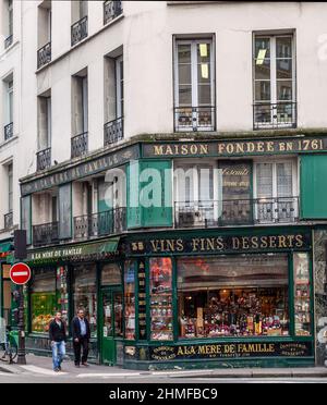 Due uomini passeggiando accanto al negozio Á la Mére de Famille, un negozio di belle Epoque che vende vini pregiati, prodotti al cioccolato e dolciumi. Rue du Faub Foto Stock
