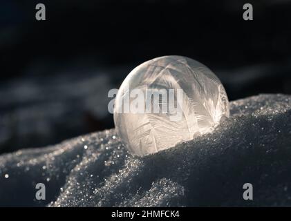 Primo piano della bolla di sapone congelato all'aperto nella neve in una giornata fredda. Foto Stock