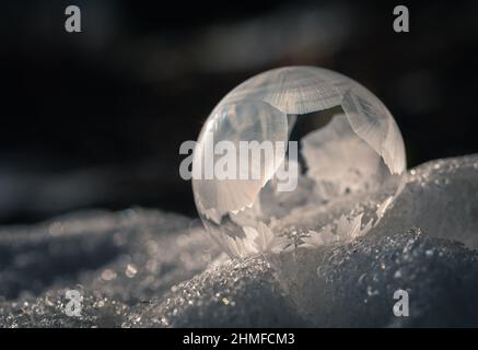 Primo piano della bolla di sapone congelato all'aperto nella neve in una giornata fredda. Foto Stock