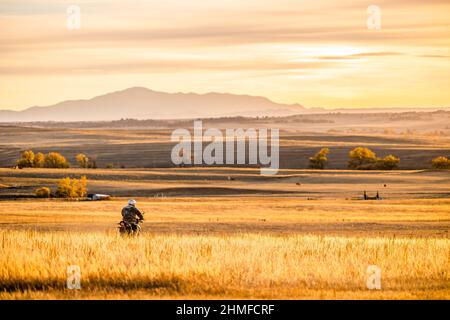 Uomo in bici da terra all'ora d'oro con Pike's Peak in Colorado Foto Stock