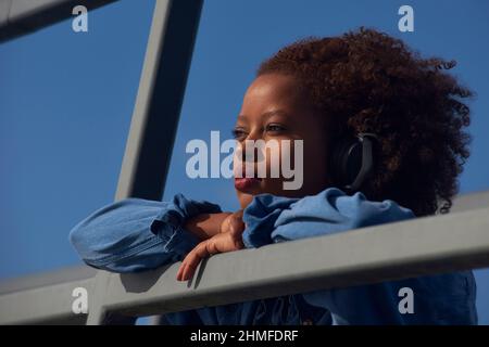 Ritratto di una giovane donna nera con grandi capelli afro indossando le cuffie Foto Stock