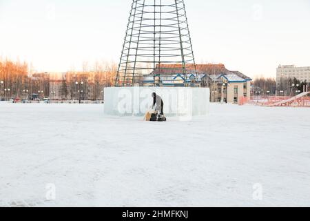 Un lavoratore in giacca invernale con cappuccio e cappuccio in lana di tessuto con visiera sul posto di lavoro Foto Stock