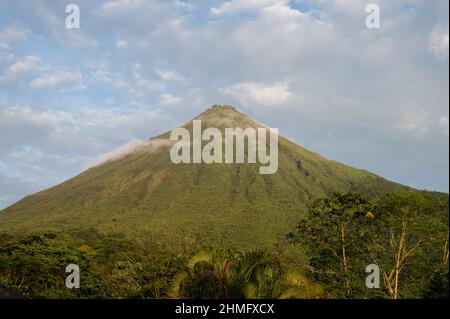 Scatto orizzontale di vista completa del vulcano Arenal verde con le nuvole hovering vicino alla città di la Fortuna in Costa Rica Foto Stock