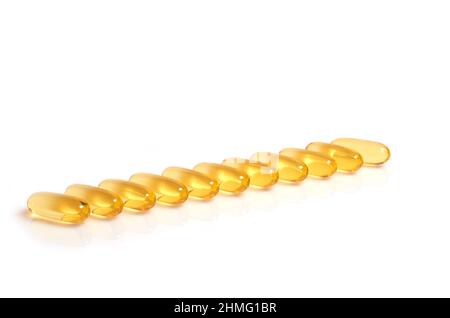 Molte capsule gialle di olio di pesce omega-3 gialle si trovano in fila Foto Stock