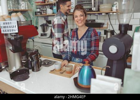 La giovane barista sorridente è al servizio della clientela Foto Stock