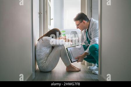 Psichiatra cercando di aiutare con empatia una paziente femminile con disturbi mentali che rifiuta aiuto in un centro di salute mentale Foto Stock