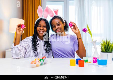 due sorelline felice con coniglietto orecchio pittura uova in appartamento preparazione a pasqua Foto Stock