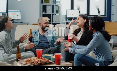 Gruppo di compagni di lavoro diversi che giocano a charades con note appiccicose sulla fronte per svolgere attività divertenti dopo il lavoro in ufficio. I colleghi si divertirono a indovinare il gioco con il tempo libero con l'intrattenimento. Foto Stock