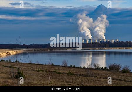 10 febbraio 2022, Brandeburgo, Cottbus: Vista sul bordo dell'ex miniera di lignite di Cottbus-Nord fino alla centrale elettrica alimentata a Jänschwalde lignite, dove il vapore sale dalle torri di raffreddamento. È qui che il futuro Cottbus East Lake sarà creato in pochi anni. L'alluvione è iniziata presso l'ex miniera a cielo aperto Cottbus-Nord a metà aprile 2019. La società di energia Lausitz Energie Bergbau AG (LEAG) consente all'acqua di fluire dallo Sprea attraverso il Hammergraben nella fossa aperta per l'allagamento, per un totale di circa 45 milioni di metri cubi all'anno. L'enorme lago artificiale è riferito di avere un Foto Stock