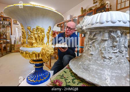 10 Febbraio 2022, Brandeburgo, Cottbus: Jens-Uwe Möbert, restauratore del Parco del Museo Fürst-Pückler e della Fondazione Castello Branitz, mette foglia d'oro sulla decorazione di un magnifico vaso crateri dal Castello di Branitz. Attualmente, il laboratorio di restauro del Parco Fürst-Pückler-Museum e della Fondazione Castle Branitz sta restaurando quattro magnifici crateri dalla terrazza del castello. Questi sono due vasi di argilla originali e due repliche. La forma del vaso è basata su antichi vasi di marmo come il famoso vaso mediceo della Galleria degli Uffizi. Pückler acquistò il vaso nel 1849 dalla fabbrica di argilla di marzo. Il p Foto Stock