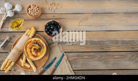 Colazione sana con hummus fatto in casa, olive nere e croccante su sfondo di legno. Dieta e snack alimentari sani. Foto Stock