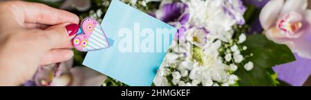 biglietto d'auguri scena mockup con la mano della donna che tiene carta bianca scheda. Bouquet di bei fiori. Invito di nozze , biglietto di auguri di compleanno Foto Stock