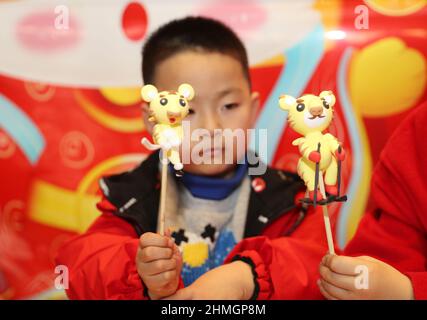 QINGDAO, CINA - 10 FEBBRAIO 2022 - Un bambino guarda una scultura di pasta fatta di ghiaccio e neve a Qingdao, provincia di Shandong della Cina orientale, febbraio 10, Foto Stock