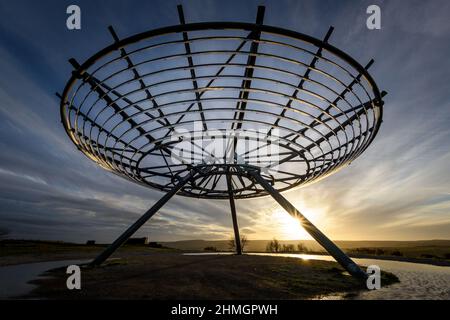 Haslingden, Lancashire, Regno Unito, mercoledì 09 febbraio 2022. Un escursionista si ferma per ammirare il sole tramontare al panopticon Halo sopra la città di Haslingden, Foto Stock