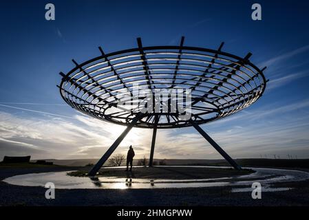 Haslingden, Lancashire, Regno Unito, mercoledì 09 febbraio 2022. Un escursionista si ferma per ammirare il sole tramontare al panopticon Halo sopra la città di Haslingden, Foto Stock