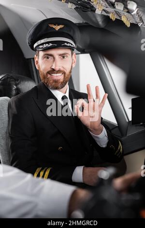 bearded pilota in uniforme mostrando bene e sorridendo quasi sfocato co-pilota Foto Stock