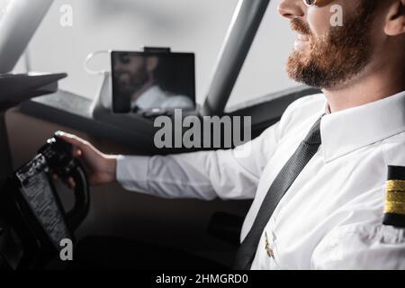 vista ritagliata del pilota allegro in uniforme con badge utilizzando il giogo Foto Stock