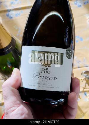 Monaco di Baviera, Germania - 9 dicembre 2021: Bottiglia di tenuta a mano POV maschio con Bio Prosecco prodotto da Valdo in Italia Foto Stock