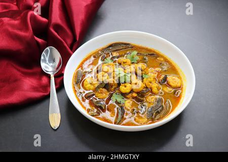 Curry di gamberi piccante e piccante. Curry di gamberi minuscoli con mango secco e spezie indiane. Guarnito con coriandolo e servito con fette di cetriolo. Foto Stock