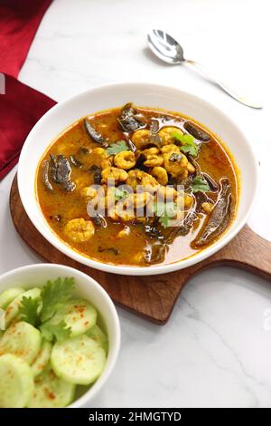 Curry di gamberi piccante e piccante. Curry di gamberi minuscoli con mango secco e spezie indiane. Guarnito con coriandolo e servito con fette di cetriolo. Foto Stock