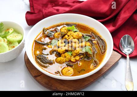 Curry di gamberi piccante e piccante. Curry di gamberi minuscoli con mango secco e spezie indiane. Guarnito con coriandolo e servito con fette di cetriolo. Foto Stock