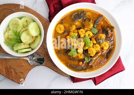 Curry di gamberi piccante e piccante. Curry di gamberi minuscoli con mango secco e spezie indiane. Guarnito con coriandolo e servito con fette di cetriolo. Foto Stock