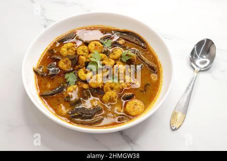 Curry di gamberi piccante e piccante. Curry di gamberi minuscoli con mango secco e spezie indiane. Guarnito con coriandolo e servito con fette di cetriolo. Foto Stock