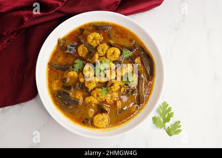 Curry di gamberi piccante e piccante. Curry di gamberi minuscoli con mango secco e spezie indiane. Guarnito con coriandolo e servito con fette di cetriolo. Foto Stock