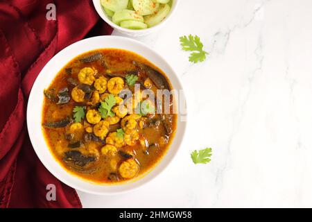 Curry di gamberi piccante e piccante. Curry di gamberi minuscoli con mango secco e spezie indiane. Guarnito con coriandolo e servito con fette di cetriolo. Foto Stock