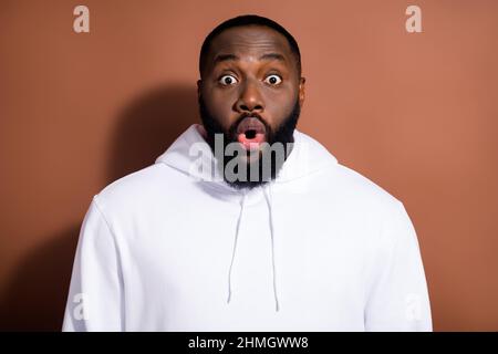 Foto di funky scioccato ragazzo vestito bianco felpa grandi occhi isolato marrone sfondo di colore Foto Stock