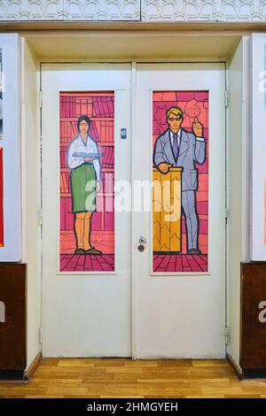 La porta della galleria presenta vetrate dipinte che guardano alla gente locale di archetipo. Insegnante e studente. Al Museo della Sanità di Tashkent, Uzbekistan. Foto Stock